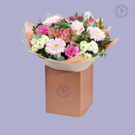 Blossom Charm Bouquet featuring pink gerbera daisies, roses, chrysanthemums, and alstroemeria in a pink gift box.