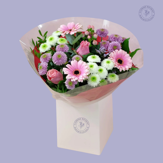 Blush Harmony Bouquet featuring pink gerbera daisies, pink roses, purple and white chrysanthemums, and eucalyptus in a white gift box.