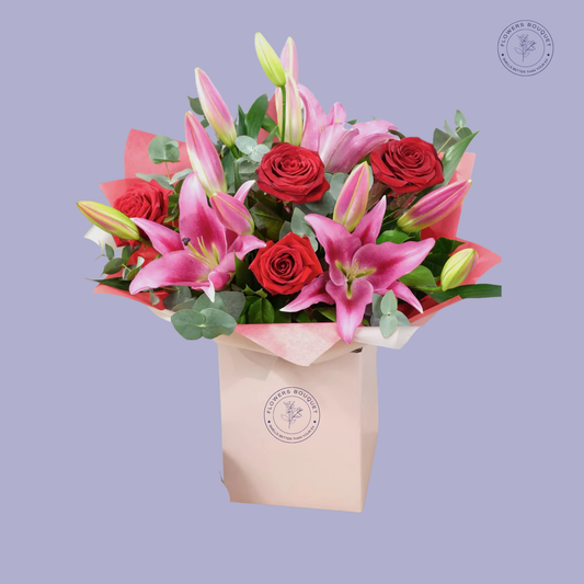 Radiant Love Bouquet featuring red roses, pink lilies, and eucalyptus in a pink gift box.