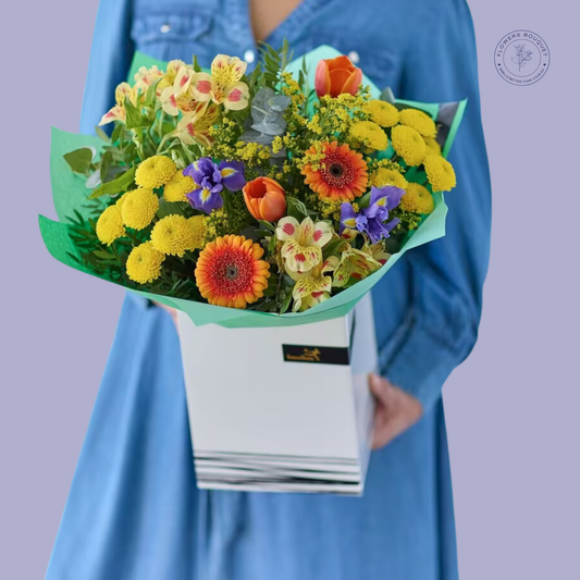 Vibrant sunflower, tulip, and iris bouquet with eucalyptus, presented in a premium white gift box.